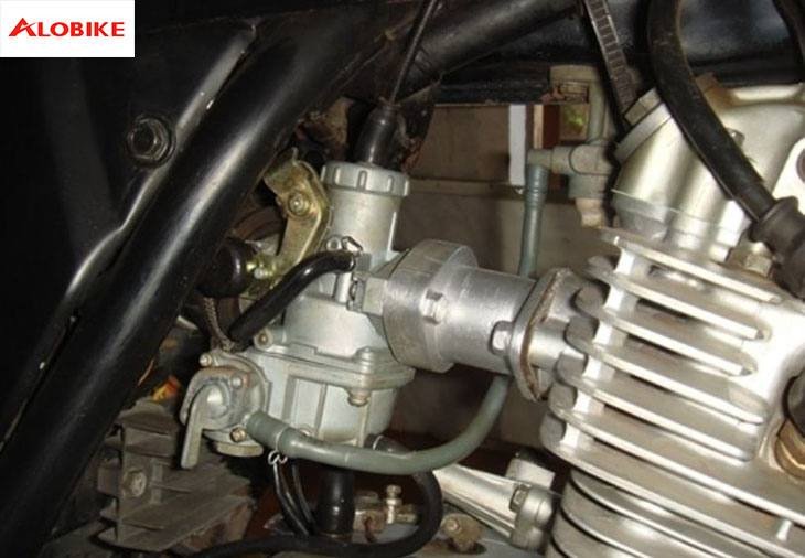 Hình ảnh một người thợ đang kiểm tra bộ chế hòa khí của xe máy để xác định tình trạng cần phục hồi