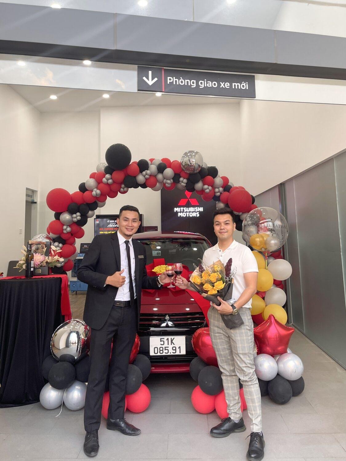 Xe Mitsubishi Attrage màu trắng đang đỗ cạnh một tòa nhà hiện đại