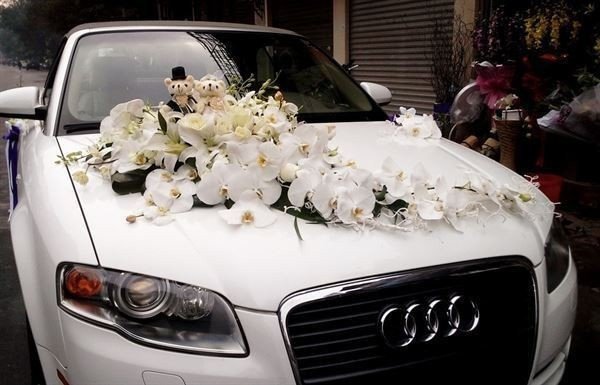 Hình ảnh cận cảnh chi tiết trang trí hoa tươi đơn giản trên mui xe hoa cưới màu trắng