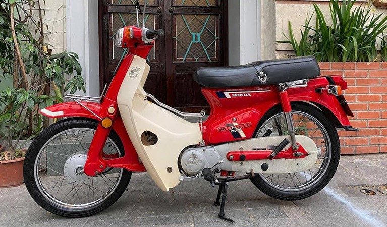 Hình ảnh chiếc Honda Cub 70 màu đỏ nổi bật trong một khung cảnh cổ điển