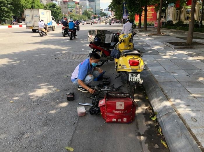 Hình ảnh kỹ thuật viên đang sửa chữa xe máy khẩn cấp trên đường