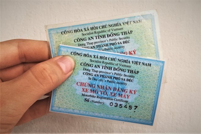 Hình ảnh minh họa chủ xe máy đang kiểm tra giấy tờ đăng ký xe