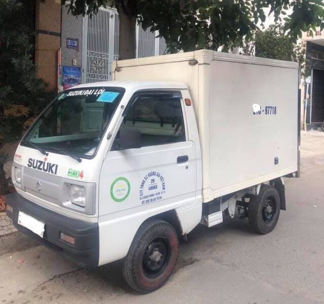 Hình ảnh minh họa một chiếc xe tải Suzuki 500kg cũ màu trắng đang đỗ trên đường phố