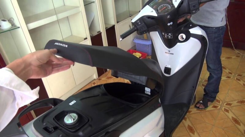 Hình ảnh minh họa một người đang cố gắng mở cốp xe máy bị khóa