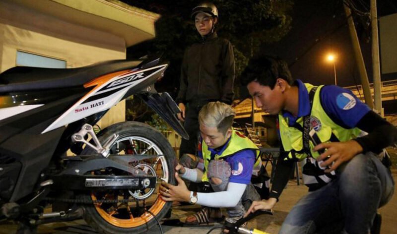 Hình ảnh một chiếc xe máy đang được kiểm tra lốp bên đường trong khu vực trung tâm thành phố