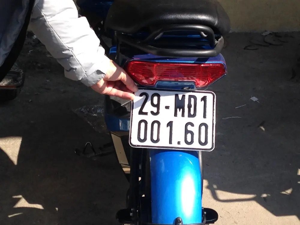 Hình ảnh một chiếc xe máy điện đã được gắn biển số hoàn chỉnh đang di chuyển trên đường