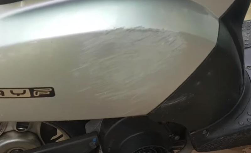 Hình ảnh một kỹ thuật viên đang kiểm tra vết xước trên thân xe máy điện