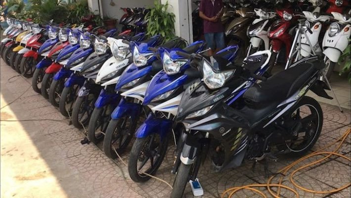 Hình ảnh một người đang đội mũ bảo hiểm chuẩn bị lên xe máy