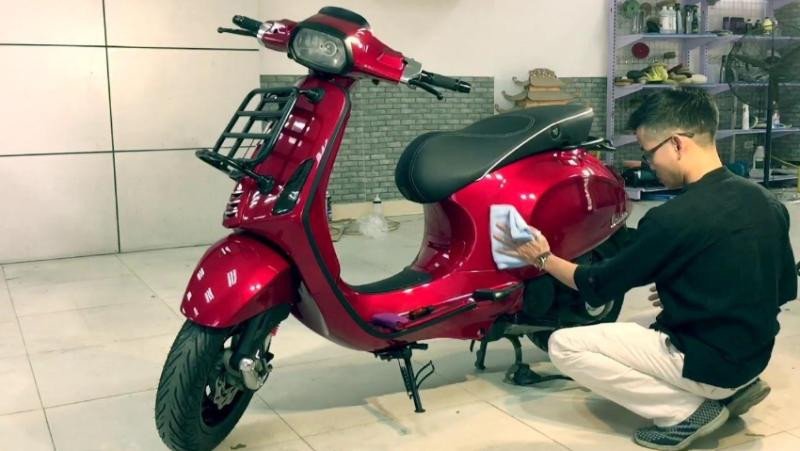 Hình ảnh một người đang sử dụng sơn Cana để làm bóng vết xước trên xe máy điện