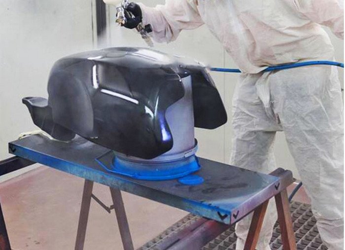 Hình ảnh một người thợ đang sử dụng dụng cụ chuyên nghiệp để sơn xe máy điện