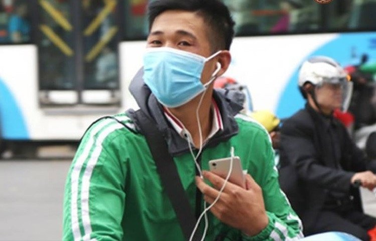 Hình ảnh người lái xe máy đeo tai nghe trong khi di chuyển trên đường