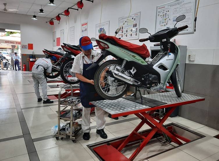 Hình ảnh người thợ đang kiểm tra và bảo dưỡng xe máy