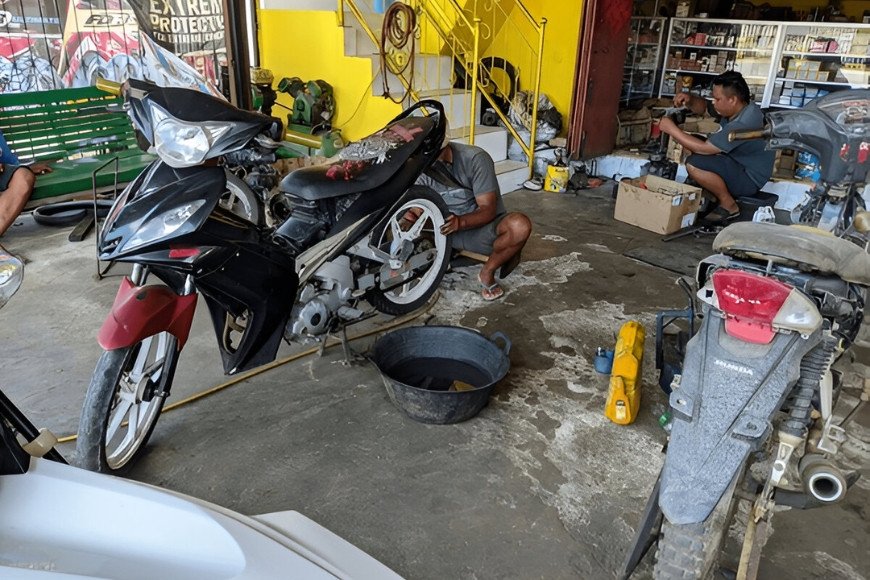 Hình ảnh nhân viên kỹ thuật đang tiến hành thay dầu nhớt cho xe máy