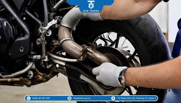 Hình ảnh thợ sửa chữa đang tiến hành kiểm tra hoặc hàn lại ống xả xe máy