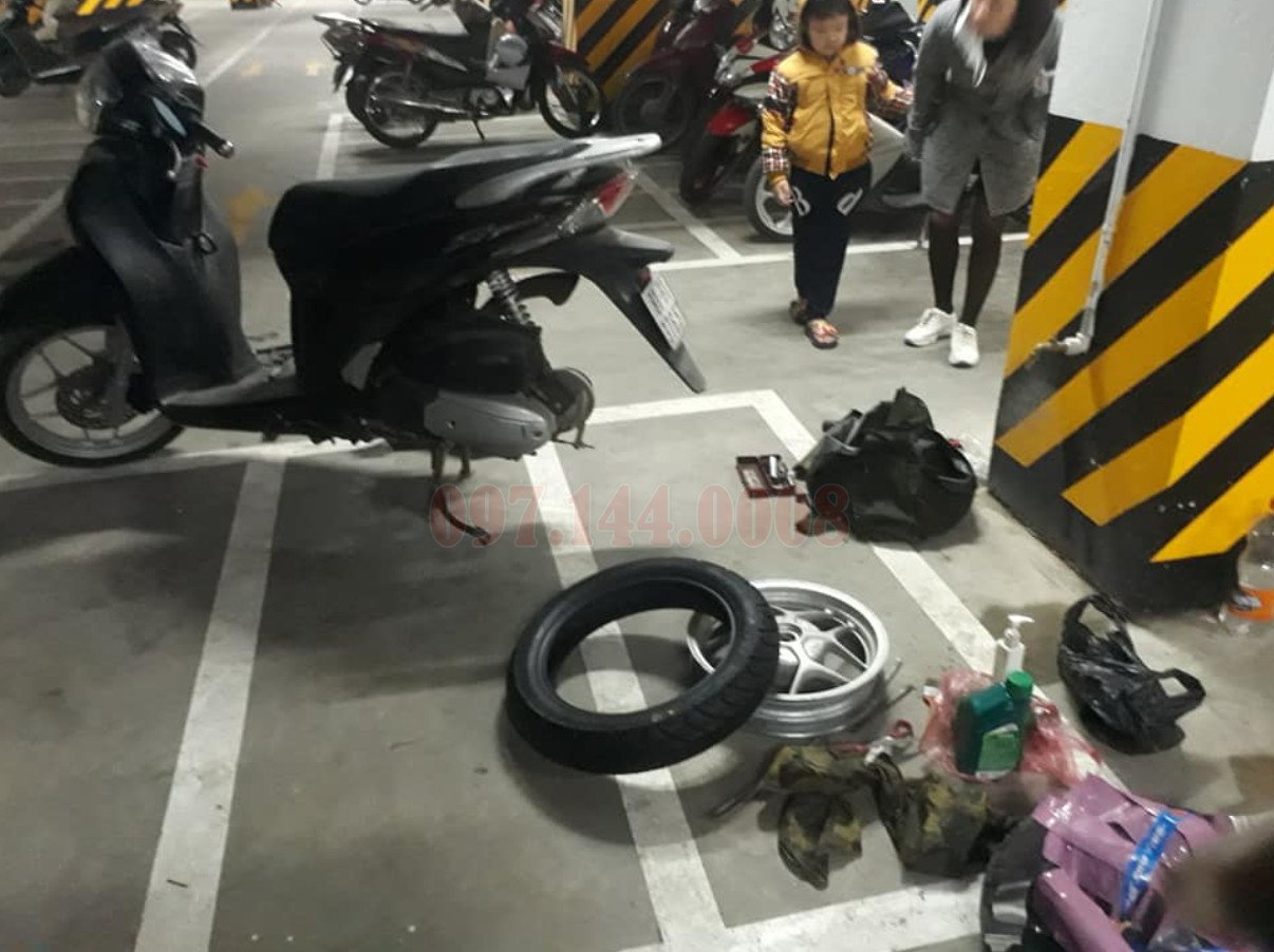 Kỹ thuật viên đang thực hiện công việc sửa chữa xe máy ngay trên vỉa hè với bộ dụng cụ chuyên nghiệp