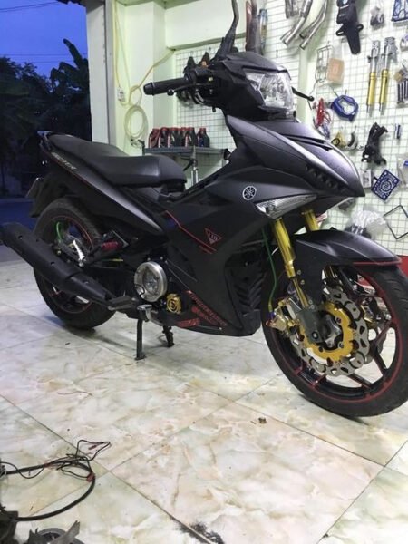 Kỹ thuật viên đang thực hiện dán decal xe máy chuyên nghiệp tại một cửa hàng