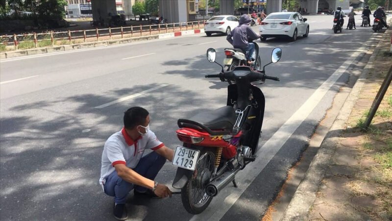 Kỹ thuật viên kiểm tra động cơ xe máy đang gặp sự cố giữa đường