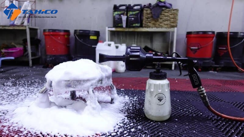 Máy phun tạo bọt tuyết đang bao phủ một chiếc xe ô tô màu trắng bằng lớp bọt dày