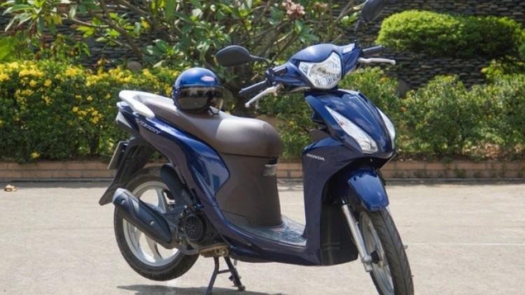 Mô tả hình ảnh: Chiếc Honda Vision màu đỏ đỗ trên vỉa hè, thể hiện sự nhỏ gọn của xe tay ga