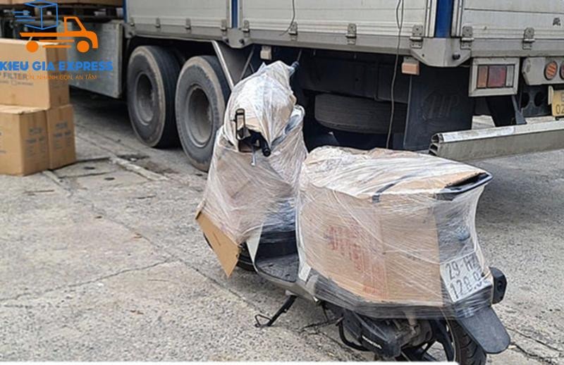Mô tả hình ảnh: Xe máy được đặt trên pallet và bọc kỹ lưỡng trước khi chất lên xe tải