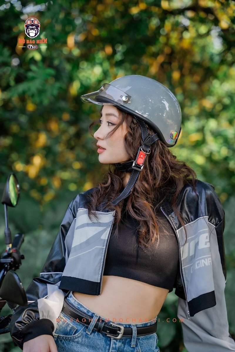 Một chiếc mũ bảo hiểm 1/2 màu đỏ tươi đang được đặt trên yên xe máy.