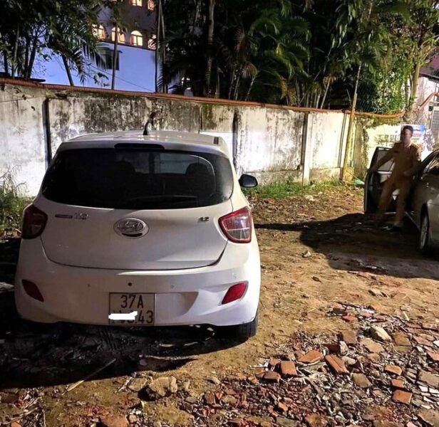 Một chiếc xe Hyundai i10 màu sáng đang di chuyển trên đường phố ban đêm