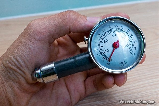 Một người đang sử dụng đồng hồ đo áp suất lốp xe máy kỹ thuật số