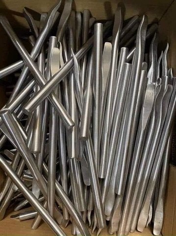 Một người thợ đang sử dụng dụng cụ móc lốp xe máy để tháo lốp