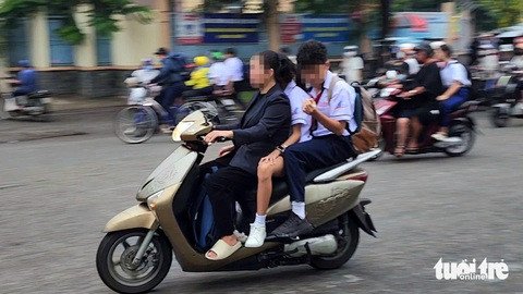 Phụ huynh không đội mũ bảo hiểm chở học sinh không đội mũ trên đường