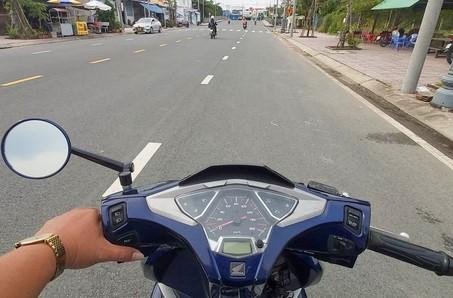 Phụ nữ lái xe máy kiểm tra gương chiếu hậu bên trái