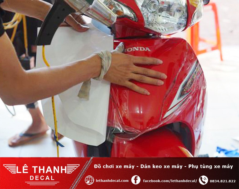 Quá trình dùng máy sấy tóc để làm mềm và gỡ lớp keo cũ trên xe