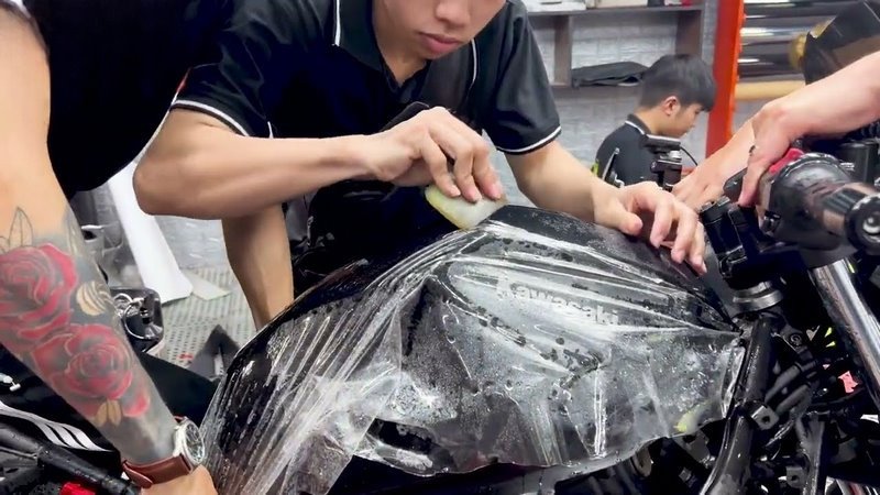 Thao tác dán film PPF lên bề mặt dàn áo xe máy
