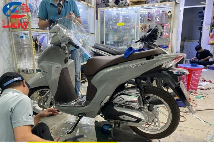 Thao tác sử dụng thẻ gạt nhựa để loại bỏ bọt khí khi dán chống xước xe máy