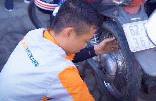Thợ sửa xe kiểm tra áp suất lốp xe máy để đảm bảo xe vận hành trơn tru