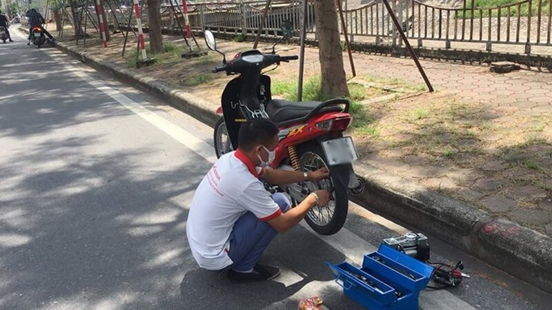 Thợ sửa xe máy đang vá lốp xe lưu động